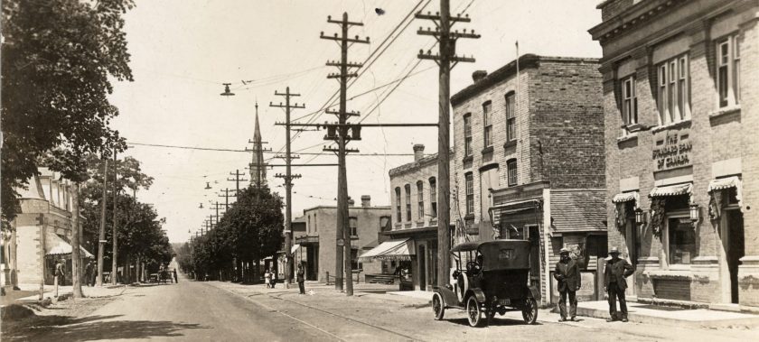 An old black and white photograph looking north on Yonge Street near the corner of Arnold Crescent featuring an old car with two men standing beside it (circa. 1915)